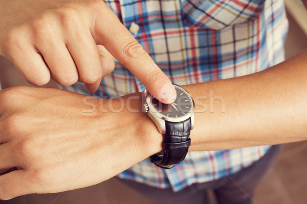 young man tapping his finger on his wristwatch  Stock photo © nito