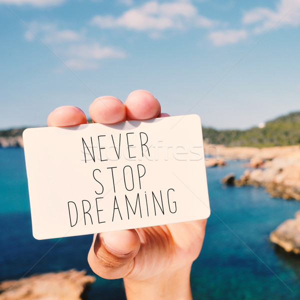 man shows a signboard with the text never stop dreaming Stock photo © nito