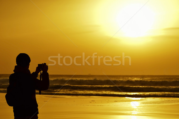 young man taking a picture in front of the sea at dusk Stock photo © nito