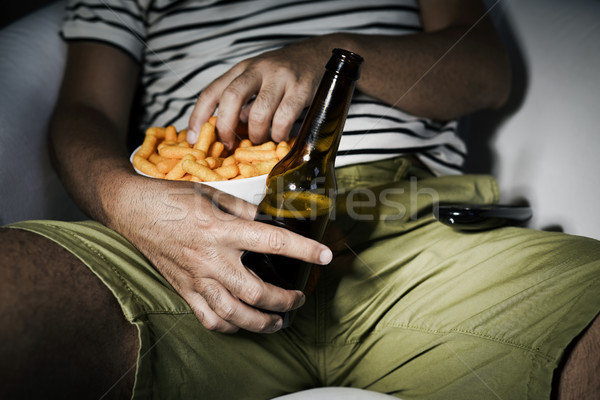 man drinking beer and eating cheese puffs Stock photo © nito