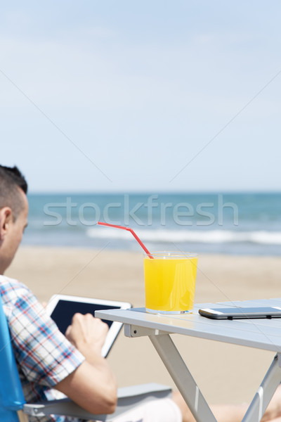 man using a tablet on the beach Stock photo © nito