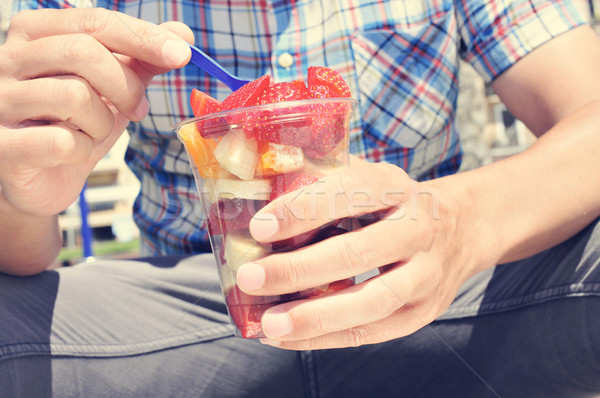 youn man eating a fruit salad outdoors Stock photo © nito