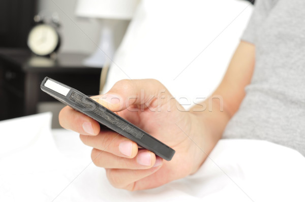 young man using a smartphone in bed Stock photo © nito