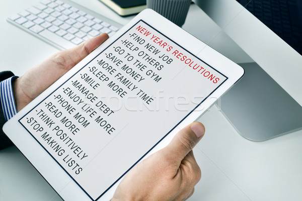 man with a list of new years resolutions in a tablet Stock photo © nito