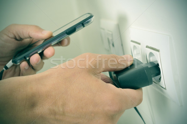 man plugging in the plug of his smpartphone in a socket, with a  Stock photo © nito