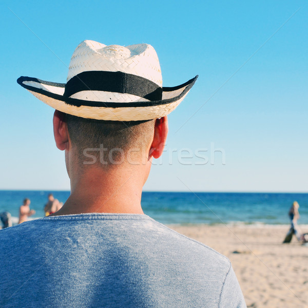 Stock photo: young man with a straw hat on the beach