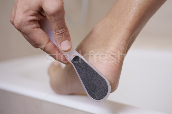 young man using a foot rasp Stock photo © nito