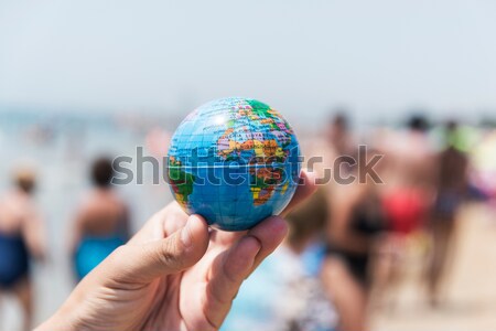 Stock photo: young man with a world globe as a christmas ball in his hand