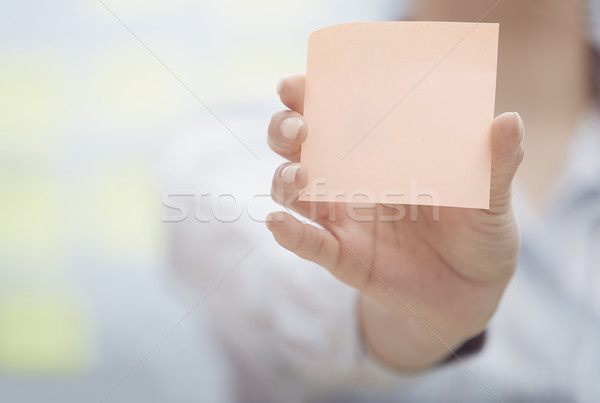 Stock photo: Hand of woman holding sticky note with empty space