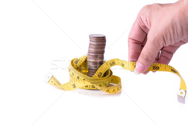 Hand holding measuring tape with stack of coins isolated on whit Stock photo © nuiiko