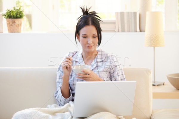 Girl in pyjama having cereal using laptop Stock photo © nyul
