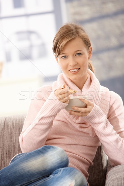 Fiatal nő eszik gabonafélék ül kanapé otthon Stock fotó © nyul