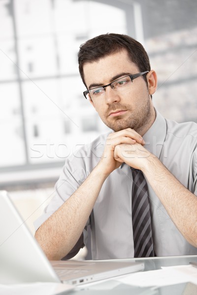 Stock photo: Portrait of young man sitting at desk using laptop