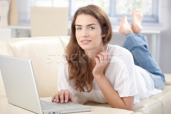 Attractive girl using laptop at home smiling Stock photo © nyul