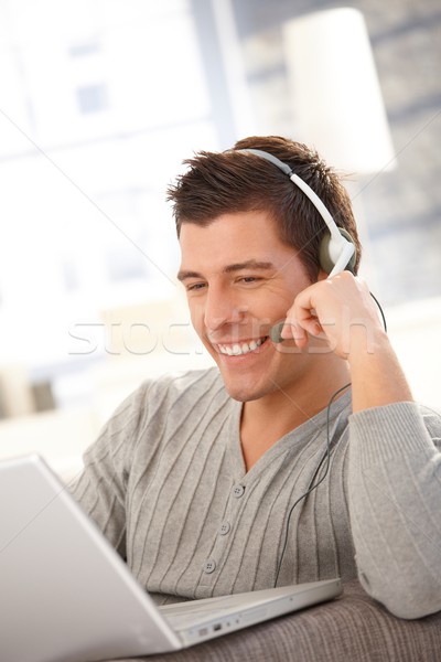 Fericit tânăr folosind laptop setul cu cască calculator vorbesc Imagine de stoc © nyul