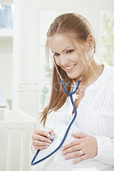 Mujer embarazada escuchar latido del corazón estetoscopio casa sonrisa Foto stock © nyul