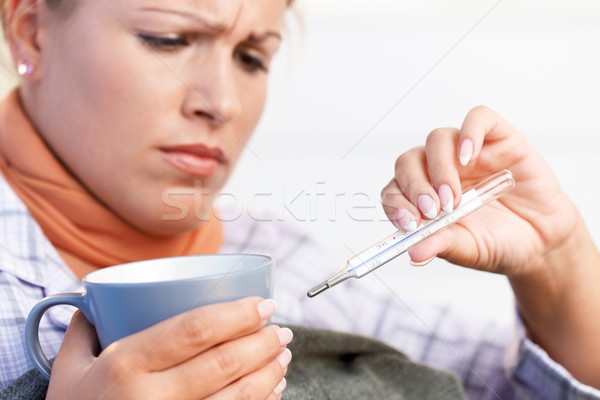 Young female having flu taking her temperature Stock photo © nyul