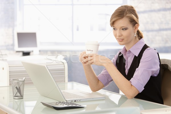 Stock photo: Young businesswoman drinking coffee at desk