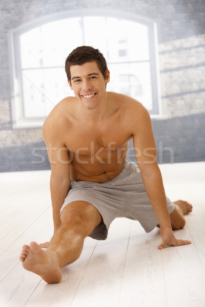 Stock photo: Masculine guy doing forward split in gym