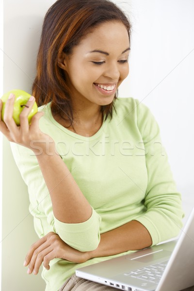 Сток-фото: счастливая · девушка · яблоко · зеленый · глядя · портативного · компьютера · экране