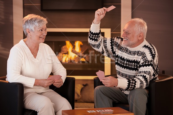 Stock photo: Retired couple playing cards in front of fireplace