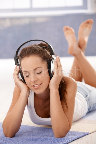 Pretty girl enjoying music laying on floor Stock photo © nyul