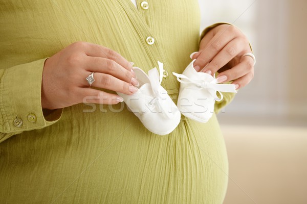 Stock photo: Pregnant woman with baby shoes