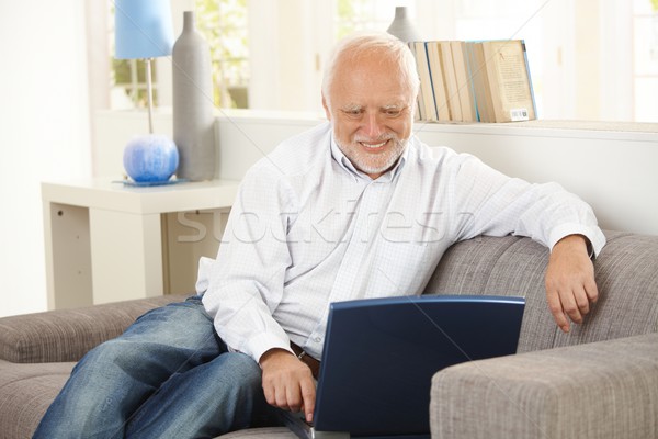 Older man smiling at computer screen at home Stock photo © nyul