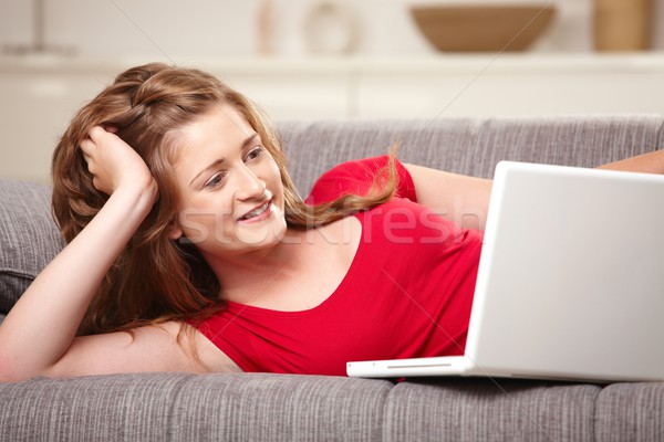 Smiling teen with laptop on sofa at home Stock photo © nyul