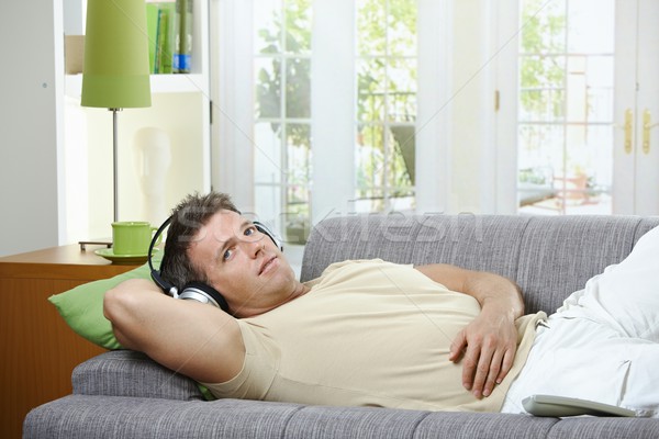 Stock photo: Man on sofa listening to music smiling