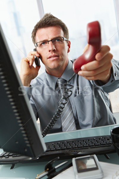 Businessman talking on cell holding landline Stock photo © nyul