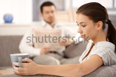 Young woman sitting on sofa man in background Stock photo © nyul