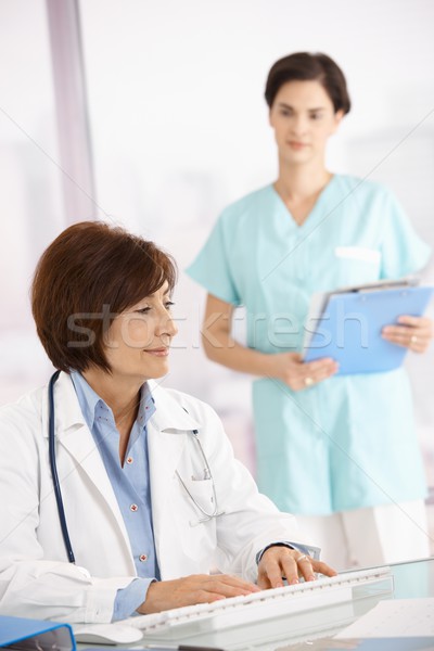 Senior doctor working at desk with assistant Stock photo © nyul