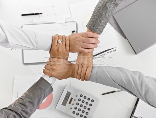 Stock photo: Four hands together in unity at businessmeeting