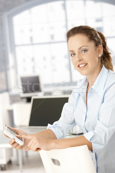 Attractive woman using mobile in office smiling Stock photo © nyul