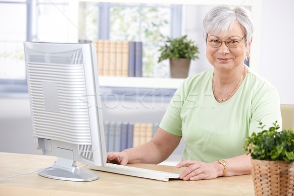 Mature lady with computer smiling Stock photo © nyul