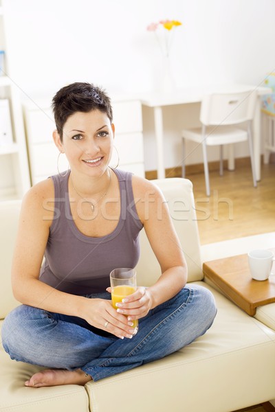 Donna bere succo d'arancia seduta divano Foto d'archivio © nyul
