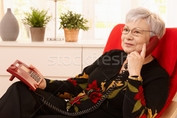 Pensionato donna telefono seduta poltrona soggiorno Foto d'archivio © nyul