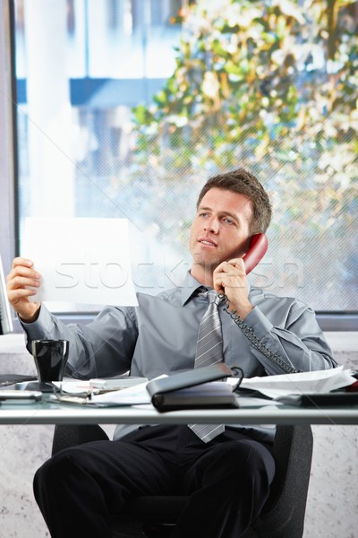 Businessman on call looking at paper Stock photo © nyul