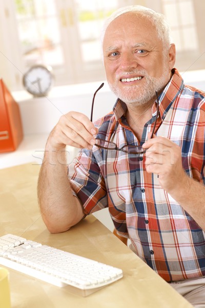 Older man putting on glasses at desk Stock photo © nyul