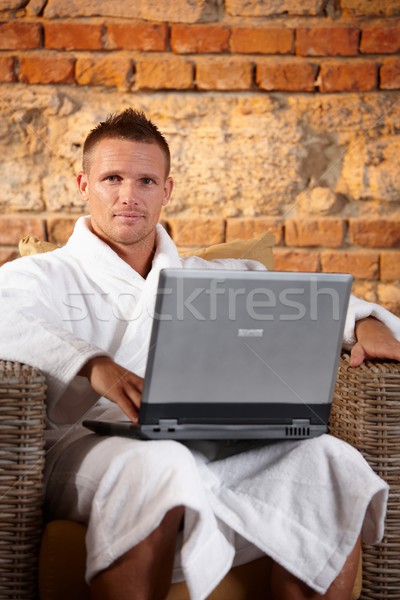Przystojny mężczyzna kąpielowy szlafrok portret posiedzenia fotel laptop Zdjęcia stock © nyul