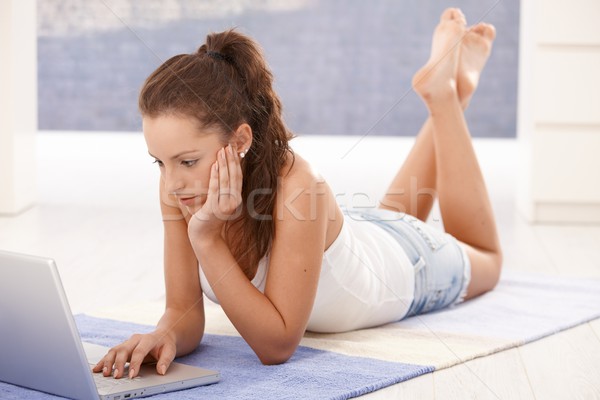 Stock photo: Attractive young girl using laptop at home
