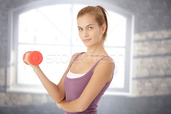 Mosolyog sportos nő súlyzó testmozgás néz Stock fotó © nyul