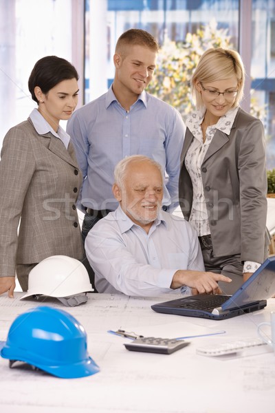 Stock photo: Senior architect showing work to team on laptop