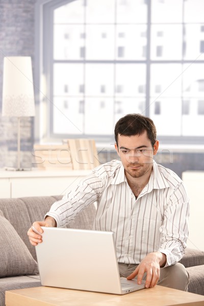 Stock photo: Young man using laptop at home sitting on sofa