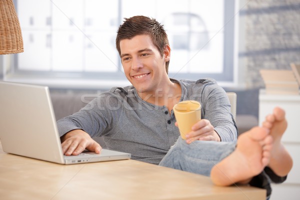 Laughing young man using computer at home Stock photo © nyul