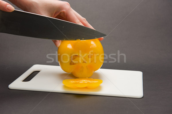 Stock photo: Woman slices yellow pepper on chopping board