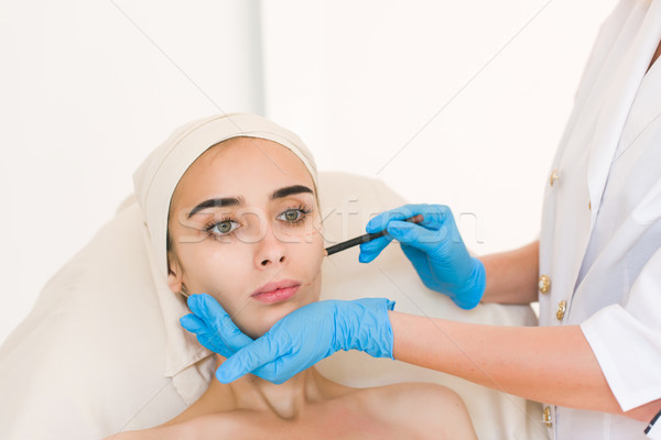 Doctor drawing marks on female face Stock photo © O_Lypa