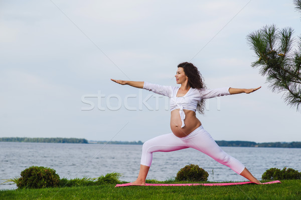 Stock photo: Pregnant woman is practicing yoga beside river