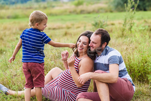 Child tickles his pregnant mother a blade of grass Stock photo © O_Lypa